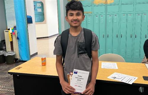 student smiling holding an amplify your voice booklet